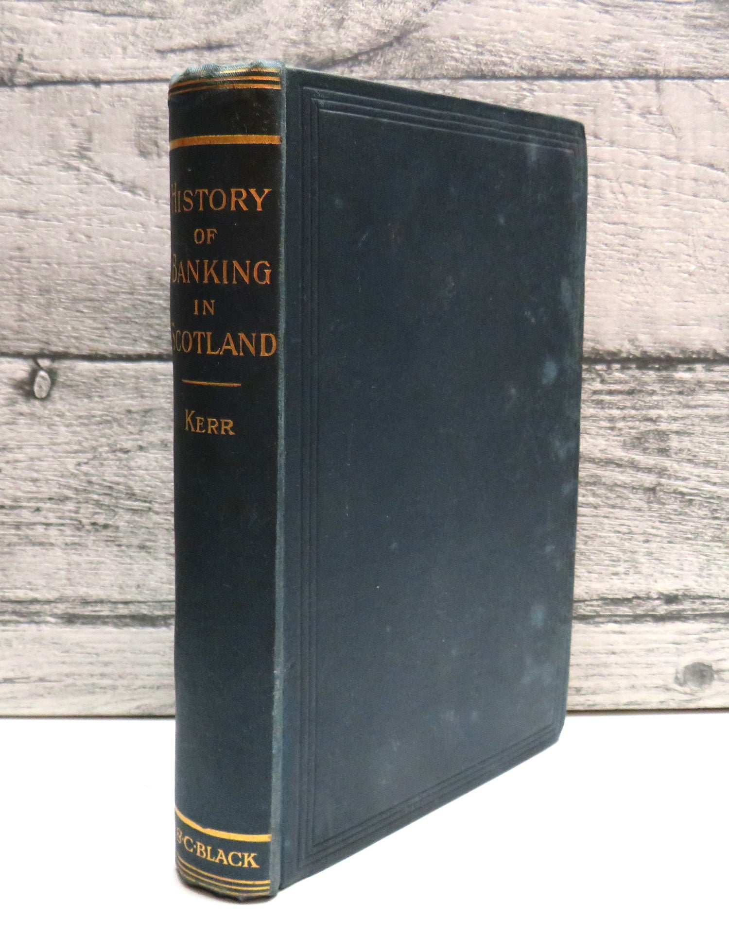 Vintage book titled 'History of Banking in Scotland' with gold lettering on a wooden surface
